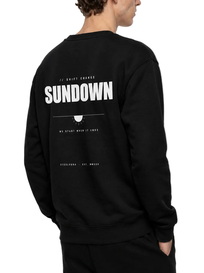 Back angled view of the Steelvora SUNDOWN oversized black crewneck sweatshirt featuring the large white SUNDOWN graphic print.